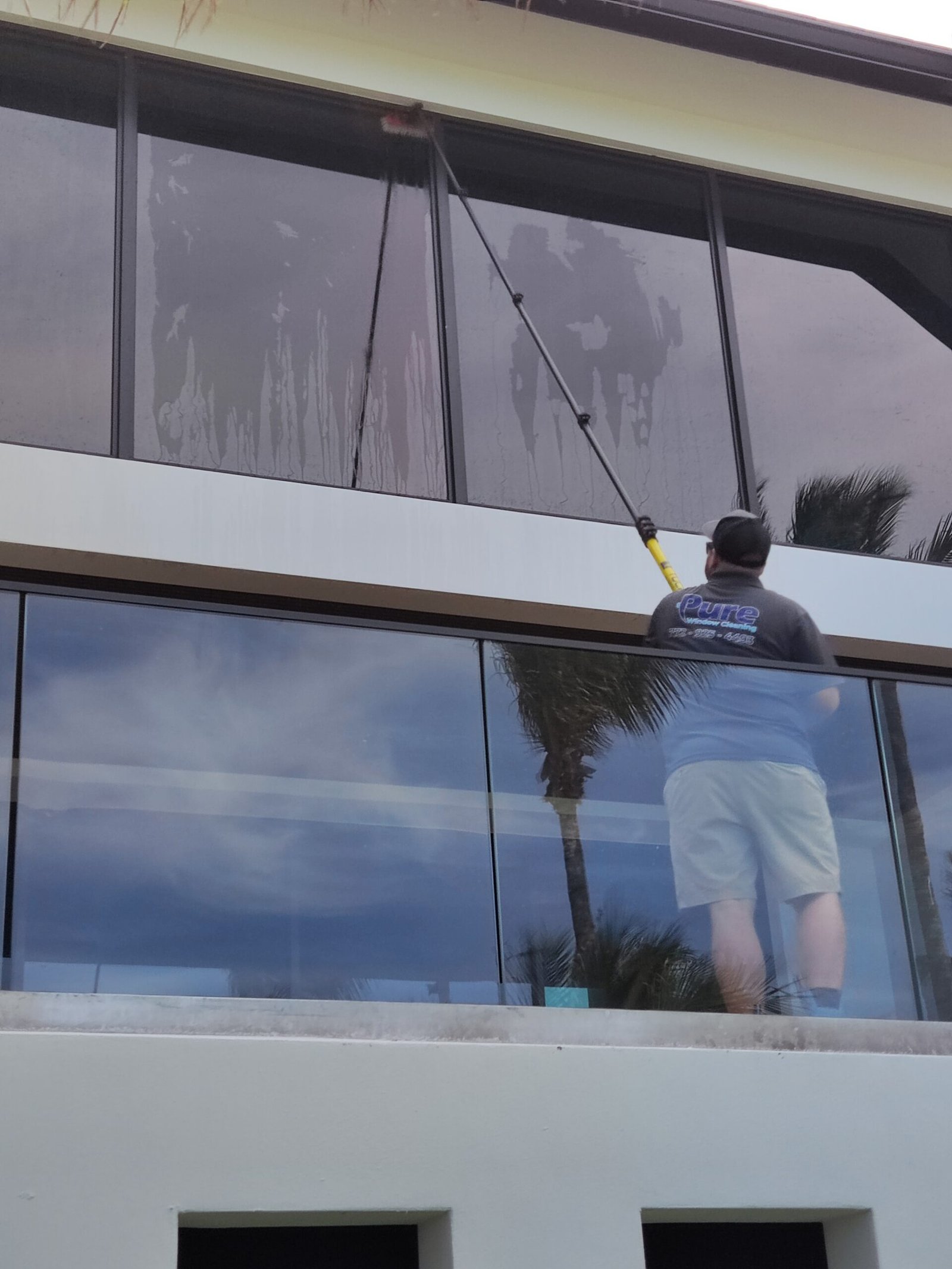 Matthew using a water-fed pole to clean windows on a luxury oceanfront home in Indian River Shores, Florida